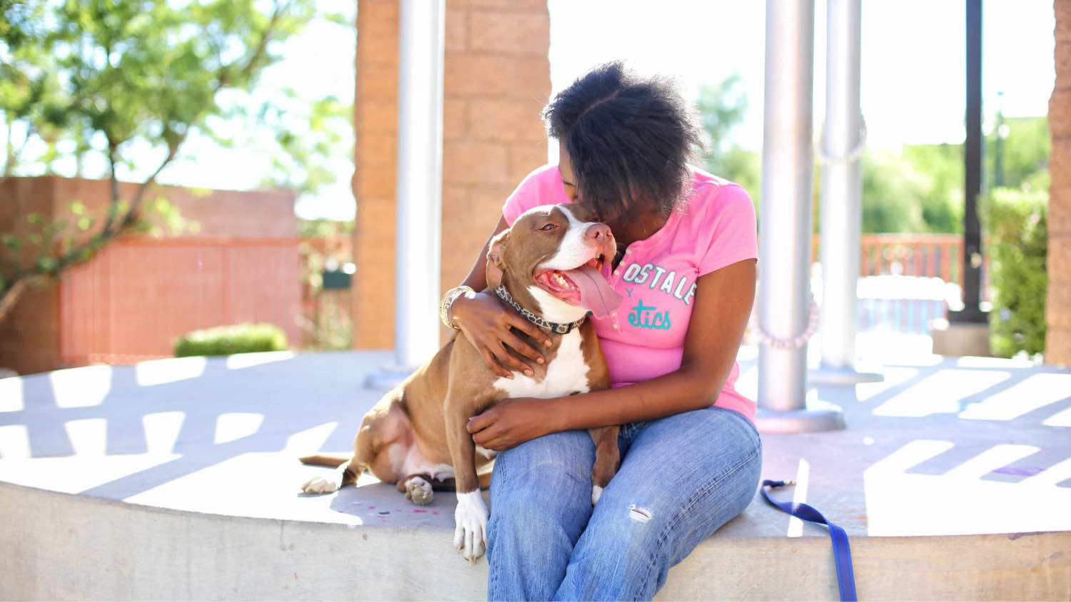 A woman sitting down with her smiling Pitbull