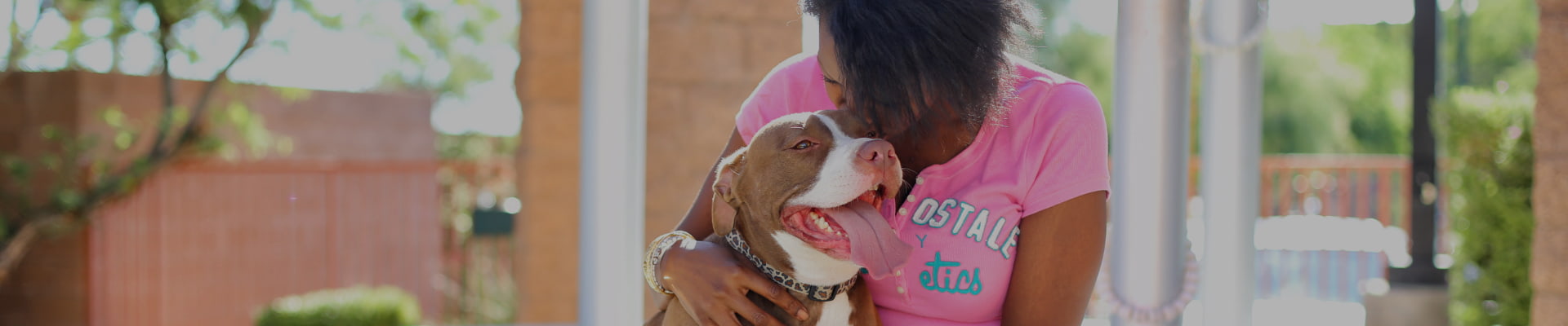 A woman sitting down with her smiling Pitbull